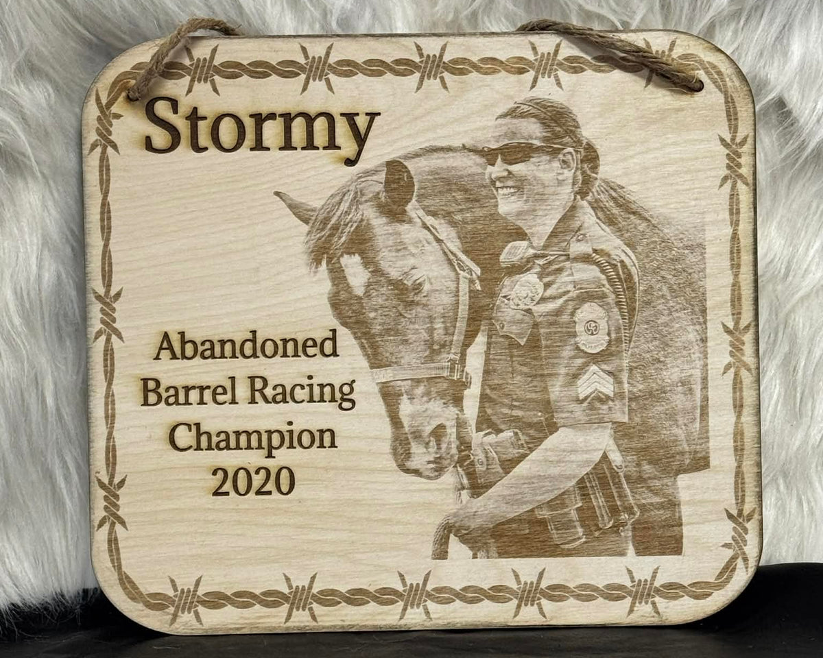 Wooden plaque with a engraved image of a person and horse, text 'Stormy Abandoned Barrel Racing Champion 2020' on a textured background.