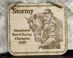 Wooden plaque with a engraved image of a person and horse, text 'Stormy Abandoned Barrel Racing Champion 2020' on a textured background.